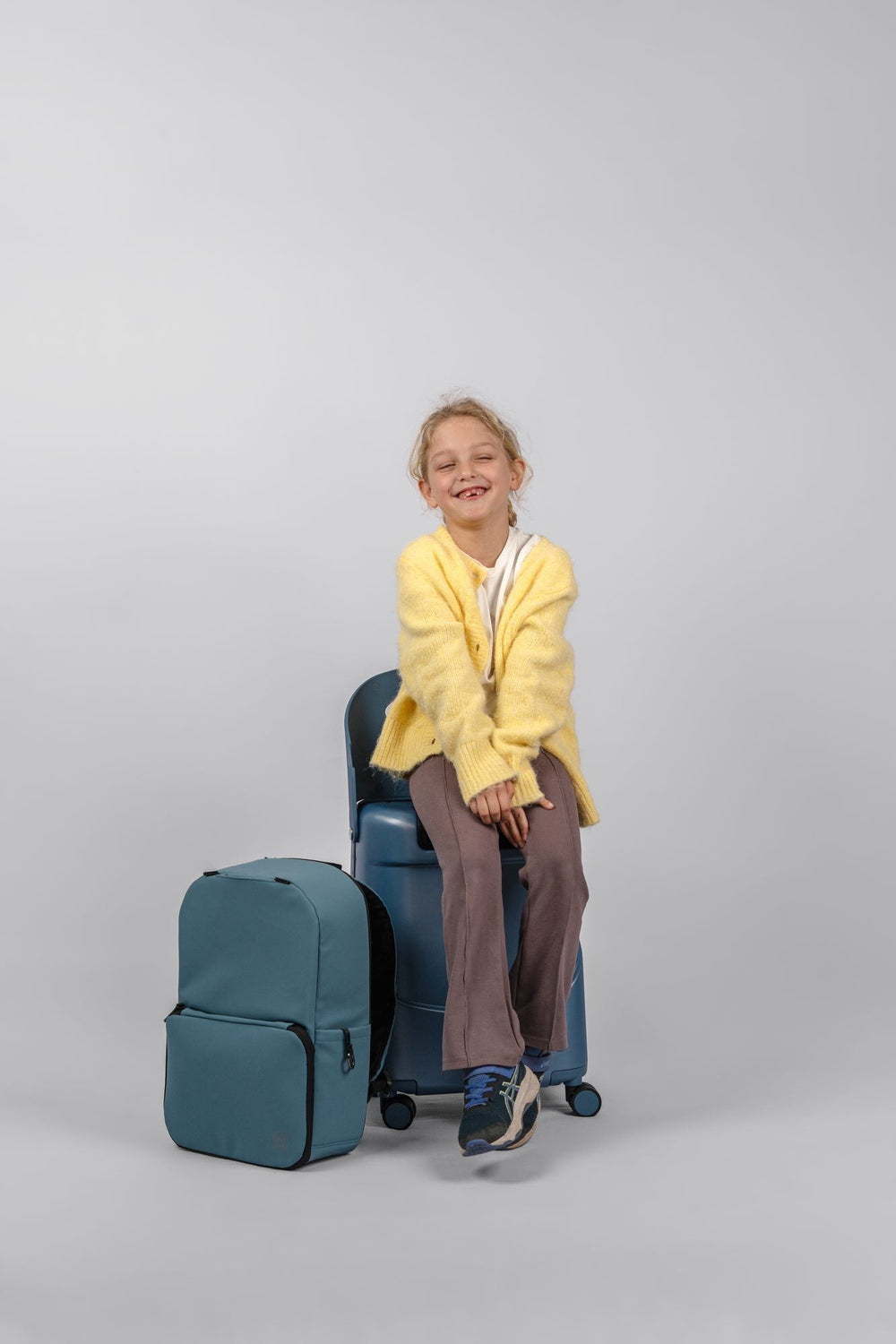 A child seated on a MiaMily Carry On with a backpack