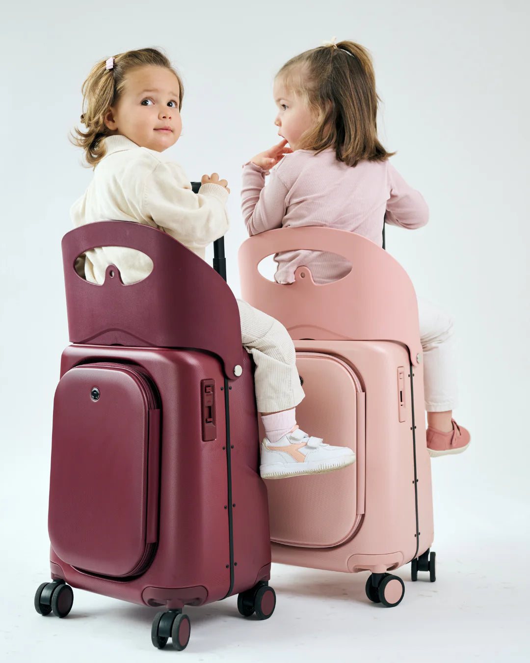 Two children riding Dusty Pink and Burgundy Red cases
